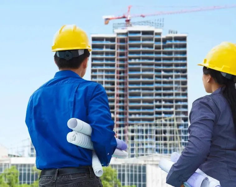 Two men in hard hats looking at a building